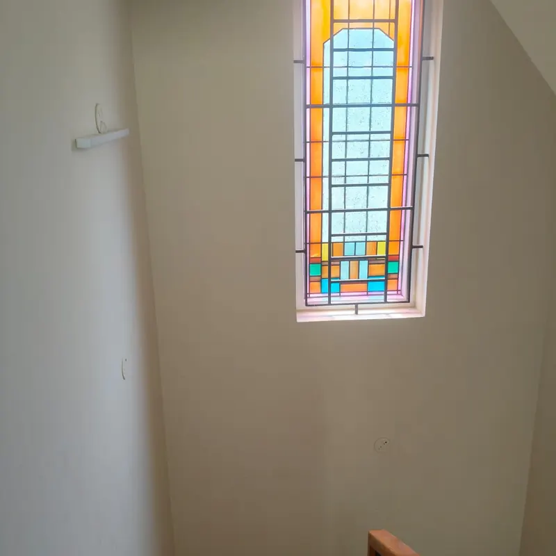 Stained glass stairwell window with a black grille